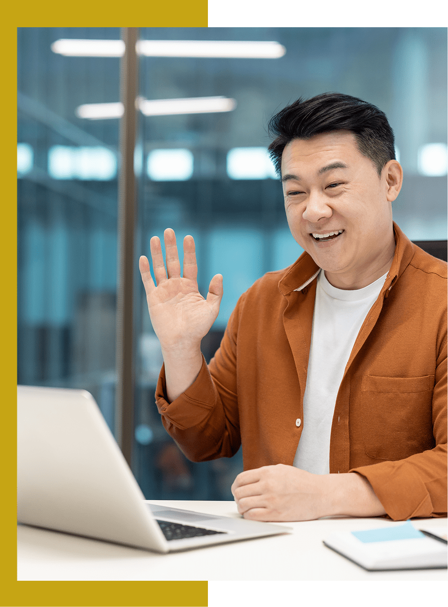 Man waving during video call at laptop.