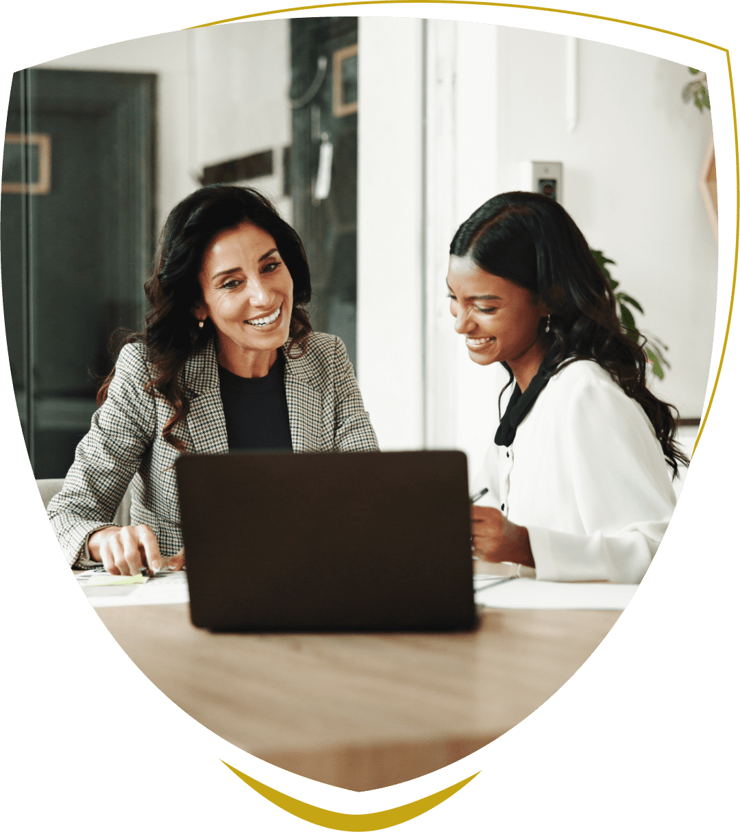 Two women smiling at a laptop.