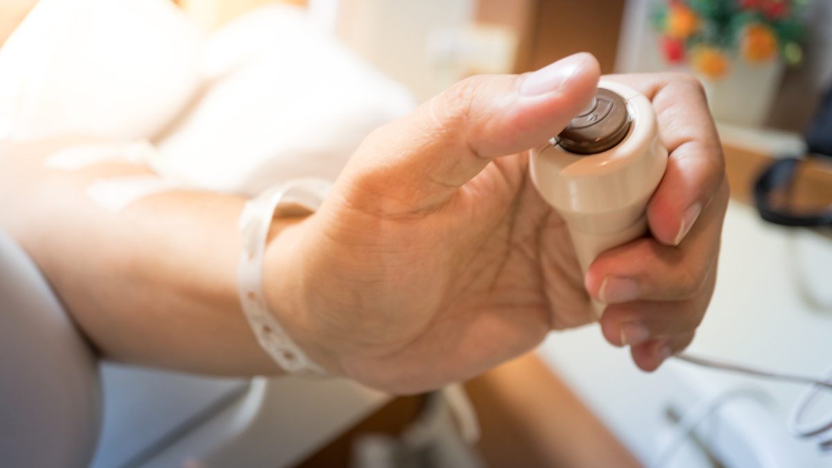 Hand holding a hospital call button.