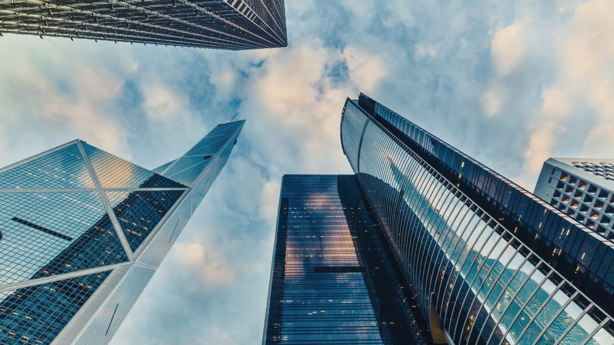 Looking up at modern skyscrapers, cloudy sky.